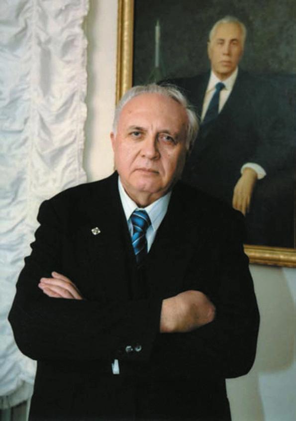 Игорь Владимирович Бармин на фоне портрета своего отца, Владимира Павловича